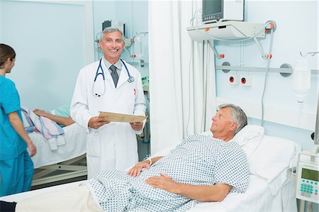 doctor scrubs patient smile - Smiling doctor with a patient in a bed ward Stock Photo - Premium Royalty-Free, Code: 6109-06196254