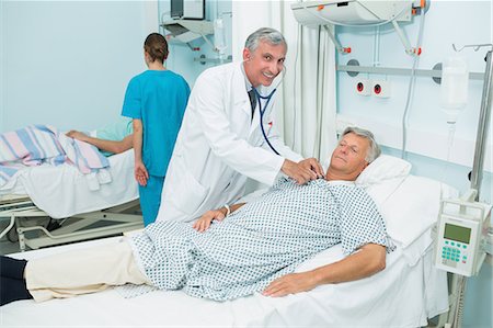 simsearch:6109-06196377,k - Lächelnd männlichen Arzt einen männlichen Patienten in ein Bett Ward auscultating Stockbilder - Premium RF Lizenzfrei, Bildnummer: 6109-06196260