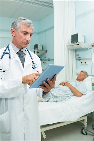 simsearch:6109-06196263,k - Doctor using a tactile tablet while standing Stock Photo - Premium Royalty-Free, Code: 6109-06196283