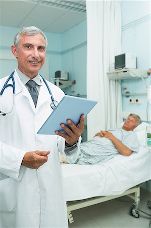 simsearch:6109-06196338,k - Happy doctor with a tactile tablet while standing Stock Photo - Premium Royalty-Free, Code: 6109-06196282