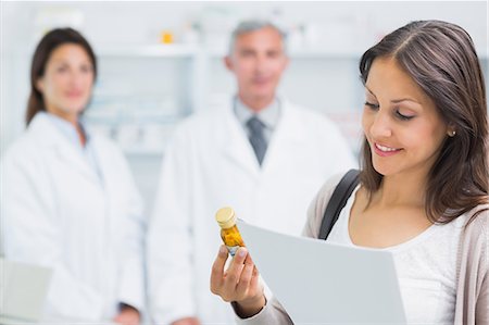 store client - Female customer holding a paper and pills while standing in a pharmacy Stock Photo - Premium Royalty-Free, Code: 6109-06196214