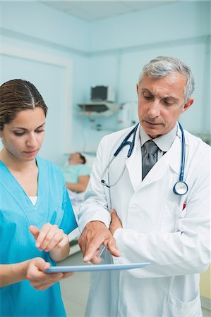 doctor close up - Infirmière et un médecin touche une tablette tactile dans un hôpital avec des patients Photographie de stock - Premium Libres de Droits, Code: 6109-06196347