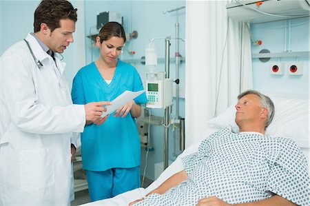 Médecin et une infirmière en regardant un papier avec un patient Photographie de stock - Premium Libres de Droits, Code: 6109-06196356