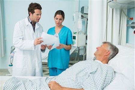 simsearch:6109-06195942,k - Doctor and female nurse holding a sheet of paper and talking to a male patient Stock Photo - Premium Royalty-Free, Code: 6109-06196360