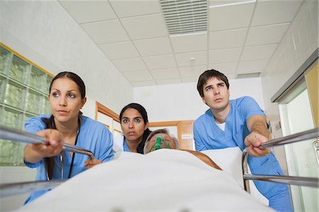 female patient oxygen - Medical team wheeling the bed of a patient in a hallway Stock Photo - Premium Royalty-Free, Code: 6109-06196382