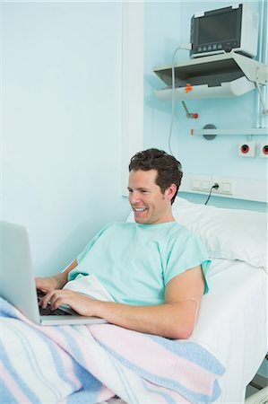 simsearch:6109-06196316,k - Joyful male patient using a laptop while lying on a bed Fotografie stock - Premium Royalty-Free, Codice: 6109-06196301