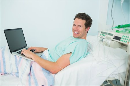 Patient using a laptop while lying on a bed Stock Photo - Premium Royalty-Free, Code: 6109-06196317