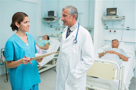 Médecin et une infirmière parlant dans un hôpital avec deux patients Photographie de stock - Premium Libres de Droits, Code: 6109-06196338