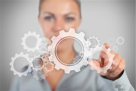 Businesswoman pressing wheels and cogs graphic Stock Photo - Premium Royalty-Free, Code: 6109-06684741