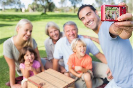 Father taking a photo of family in the park Stock Photo - Premium Royalty-Free, Code: 6109-06684797