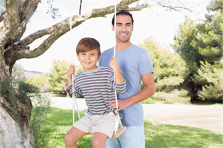 swing - Portrait of father pushing son on a swing Photographie de stock - Premium Libres de Droits, Code: 6109-06684813