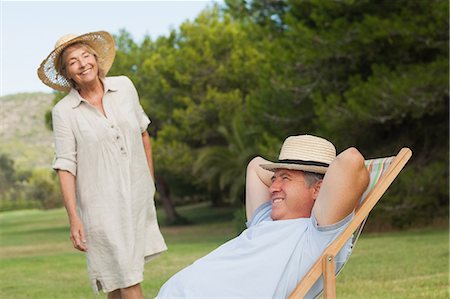 deckchair garden - Older man relaxing in deck chair with his partner approaching Stock Photo - Premium Royalty-Free, Code: 6109-06684932