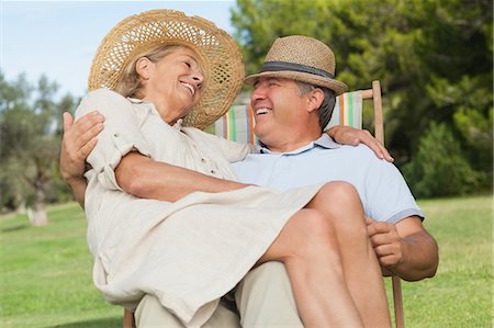 simsearch:6109-06684830,k - Woman sitting on lap of partner sitting in deck chair and smiling at him Stock Photo - Premium Royalty-Free, Code: 6109-06684936