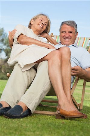 simsearch:6109-06684830,k - Older woman sitting on lap of smiling partner sitting in deck chair Stock Photo - Premium Royalty-Free, Code: 6109-06684938