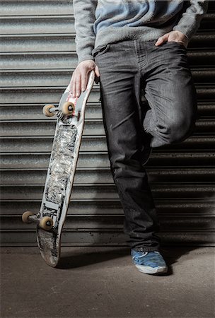 Skater standing against metal shutters Photographie de stock - Premium Libres de Droits, Code: 6109-06781442