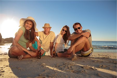 simsearch:6109-06781784,k - Smiling friends  sitting on the beach with beers Stock Photo - Premium Royalty-Free, Code: 6109-06781684