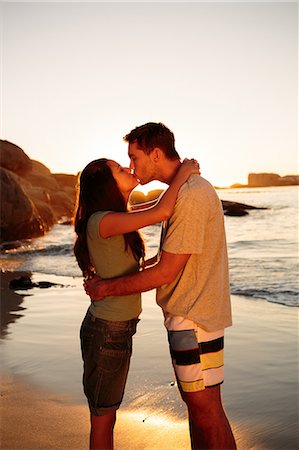 standing at sunset - Young couple embracing and kissing each other on the beach Stock Photo - Premium Royalty-Free, Code: 6109-06781693