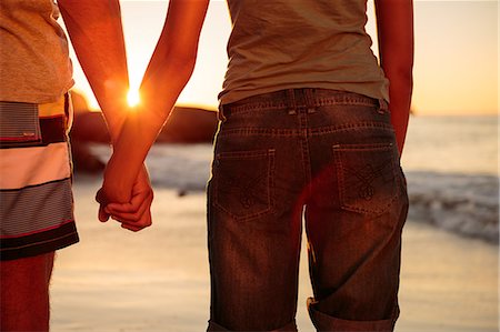 people walking on the beach sunset - Rear view of a couple hand in hand walking on the beach Photographie de stock - Premium Libres de Droits, Code: 6109-06781704