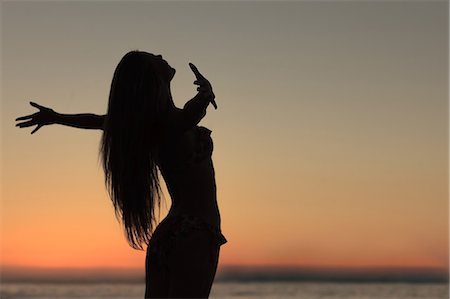 Silhouette of woman spreading her arms on the beach Stock Photo - Premium Royalty-Free, Code: 6109-06781800