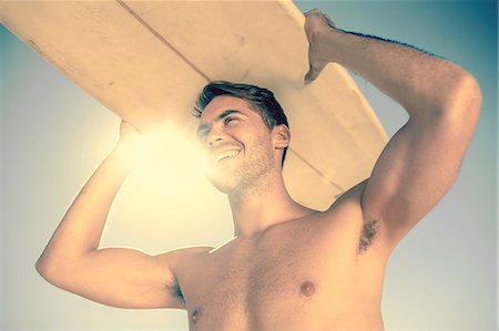 sunlight beach - Handsome man holding his surfboard above his head Stock Photo - Premium Royalty-Free, Code: 6109-06781806