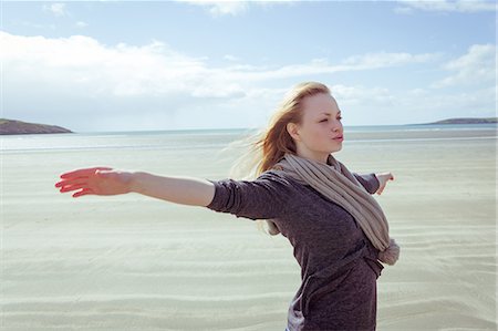 Attractive woman opening her arms in front of the ocean on the beach Stock Photo - Premium Royalty-Free, Code: 6109-07496983