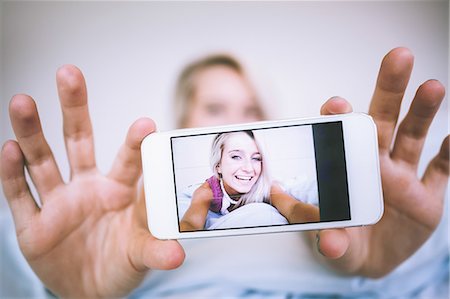 Picture on smartphone of gorgeous cheerful blonde in bright bedroom Photographie de stock - Premium Libres de Droits, Code: 6109-07497049