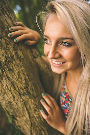 Happy gorgeous blonde leaning against tree in the woods Stock Photo - Premium Royalty-Free, Code: 6109-07497077