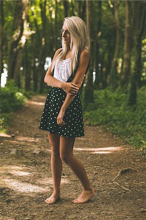 Unsmiling gorgeous blonde standing on forest track in the woods Foto de stock - Sin royalties Premium, Código: 6109-07497082