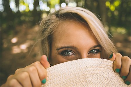 portrait natural woman - Happy gorgeous blonde holding straw hat in front of her face in the woods Stock Photo - Premium Royalty-Free, Code: 6109-07497098
