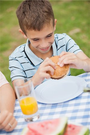 Young boy eating burger with his family in the backyard on a summers day Foto de stock - Sin royalties Premium, Código: 6109-07497008