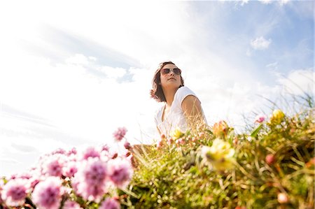 people light happy - Woman sitting in field of wild flowers reflecting on life Stock Photo - Premium Royalty-Free, Code: 6109-07497038