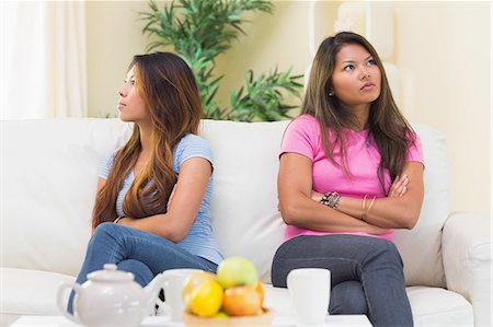 disputation - Two displeased sisters sitting on a white couch in the living room Stock Photo - Premium Royalty-Free, Code: 6109-07497144
