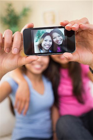 selfie photos - Two beautiful sisters taking a picture of themselves sitting on a white couch Stock Photo - Premium Royalty-Free, Code: 6109-07497163