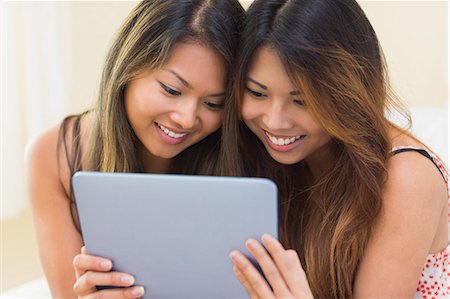 simsearch:6109-07497144,k - Two pretty sisters using a tablet while sitting on a couch in the living room Stock Photo - Premium Royalty-Free, Code: 6109-07497164