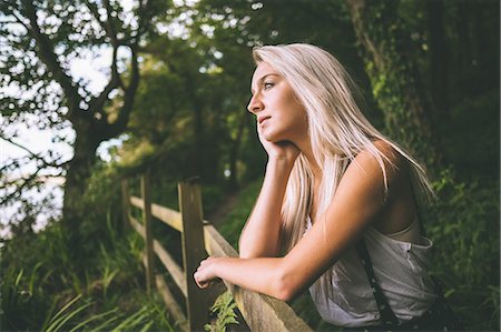 Thoughtful gorgeous blonde standing on fence in the woods Photographie de stock - Premium Libres de Droits, Code: 6109-07497105