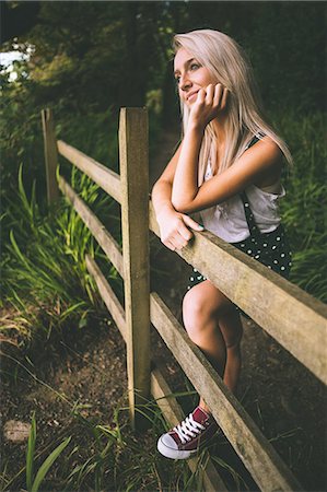 simsearch:6109-07497260,k - Smiling gorgeous blonde standing on fence in the woods Photographie de stock - Premium Libres de Droits, Code: 6109-07497106