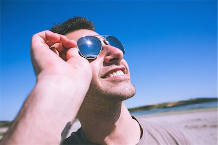 Attractive smiling man enjoying the sun on the beach Stock Photo - Premium Royalty-Free, Code: 6109-07497120