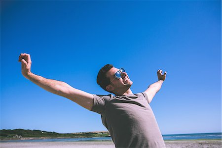 Attractive happy man enjoying the sun on the beach Stock Photo - Premium Royalty-Free, Code: 6109-07497122