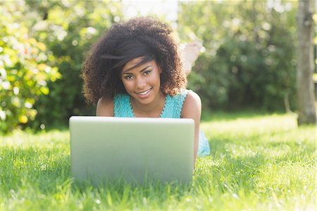 Gorgeous smiling brunette lying on grass using laptop in nature Foto de stock - Sin royalties Premium, Código: 6109-07497253