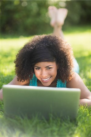 simsearch:6109-07497260,k - Gorgeous cheerful brunette lying on grass using laptop in nature Photographie de stock - Premium Libres de Droits, Code: 6109-07497255