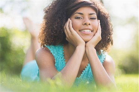 Gorgeous cheerful brunette lying on grass looking at camera in nature Stock Photo - Premium Royalty-Free, Code: 6109-07497263