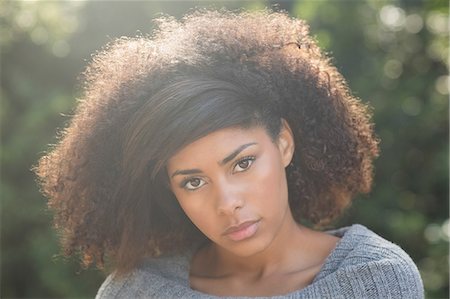 portraits of environment - Gorgeous unsmiling brunette standing in sunshine looking at camera in nature Stock Photo - Premium Royalty-Free, Code: 6109-07497287