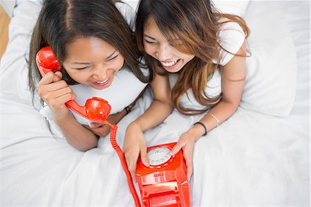 simsearch:6109-07497135,k - Two sisters making a call on an old fashioned dial phone while lying on a bed Stock Photo - Premium Royalty-Free, Code: 6109-07497202