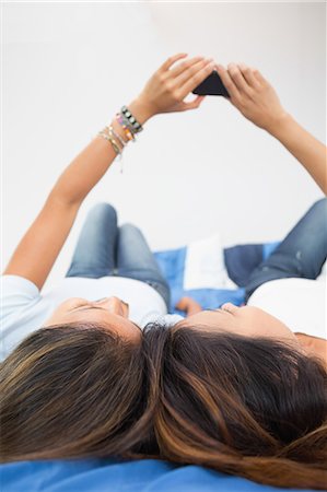 simsearch:6109-07497135,k - Two pretty sisters using a smartphone lying on bed at home Stock Photo - Premium Royalty-Free, Code: 6109-07497213