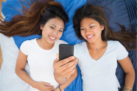 simsearch:700-06808961,k - Two pretty sisters taking a picture of themselves while lying on a bed Stock Photo - Premium Royalty-Free, Code: 6109-07497210