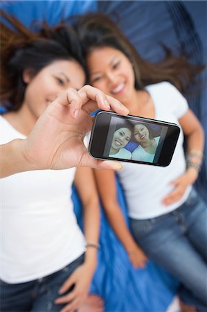 smiling friends taking picture together - Cute brunette women taking a self portrait using a smartphone Stock Photo - Premium Royalty-Free, Code: 6109-07497212