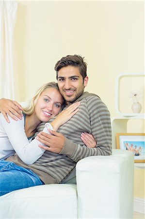 simsearch:6109-07497334,k - Calm sweet couple sitting on couch in living room looking at camera Fotografie stock - Premium Royalty-Free, Codice: 6109-07497348