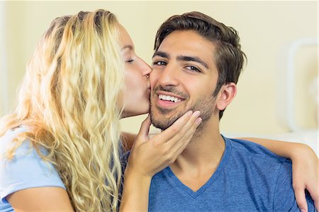simsearch:6109-07497359,k - Handsome young man being kissed by his girlfriend in the living room Fotografie stock - Premium Royalty-Free, Codice: 6109-07497354