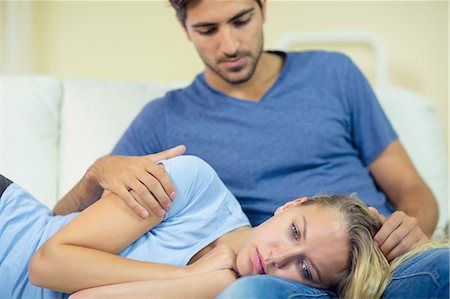 Unhappy young woman lying on the couch having her head on the lap of her boyfriend Photographie de stock - Premium Libres de Droits, Code: 6109-07497362