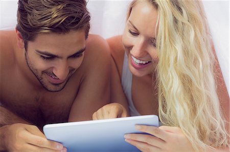 simsearch:6109-08390051,k - Amused young couple lying under the blanket making use of a tablet Foto de stock - Sin royalties Premium, Código: 6109-07497327